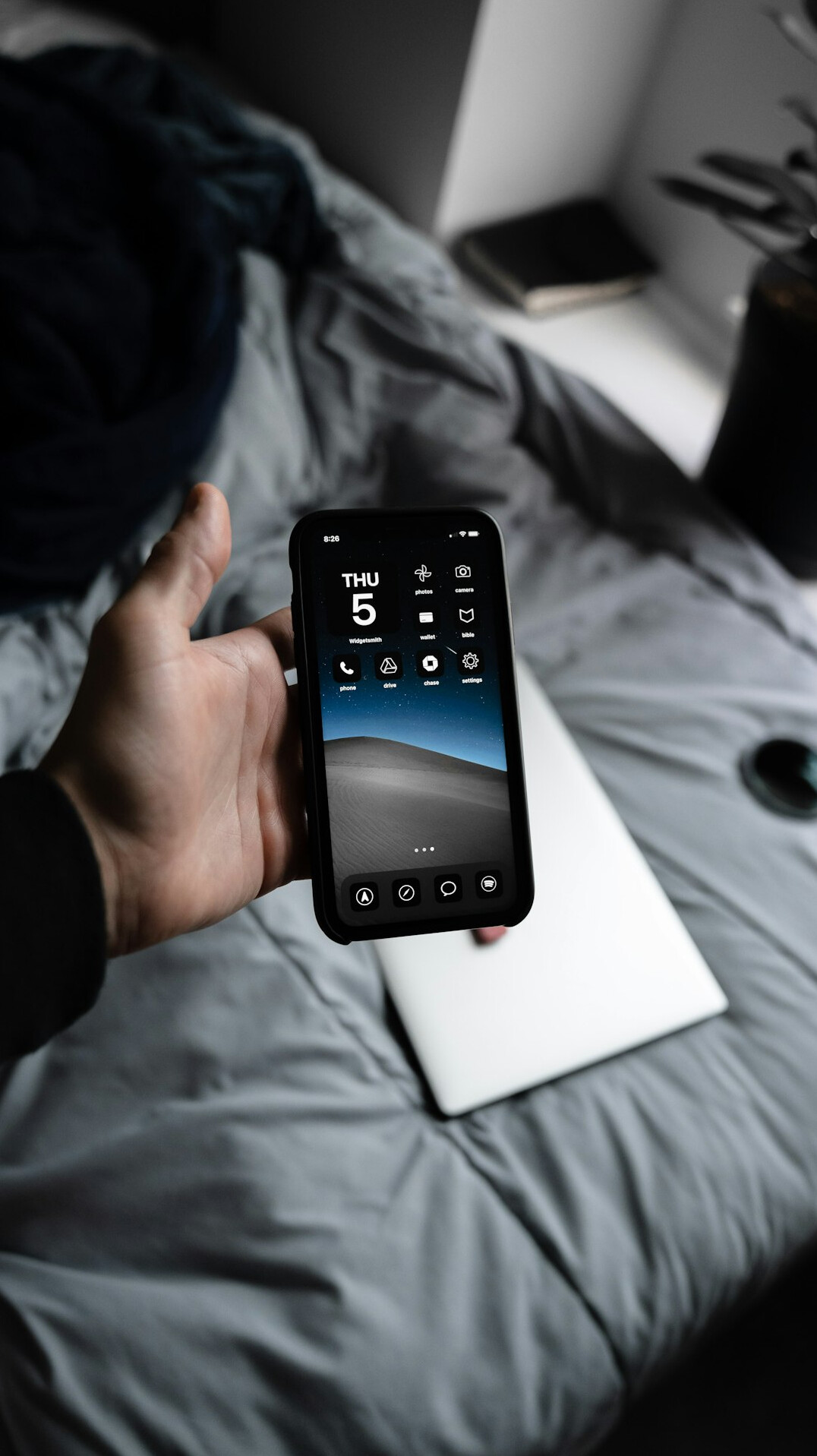 Hands holding a smartphone showing an app interface next to a laptop